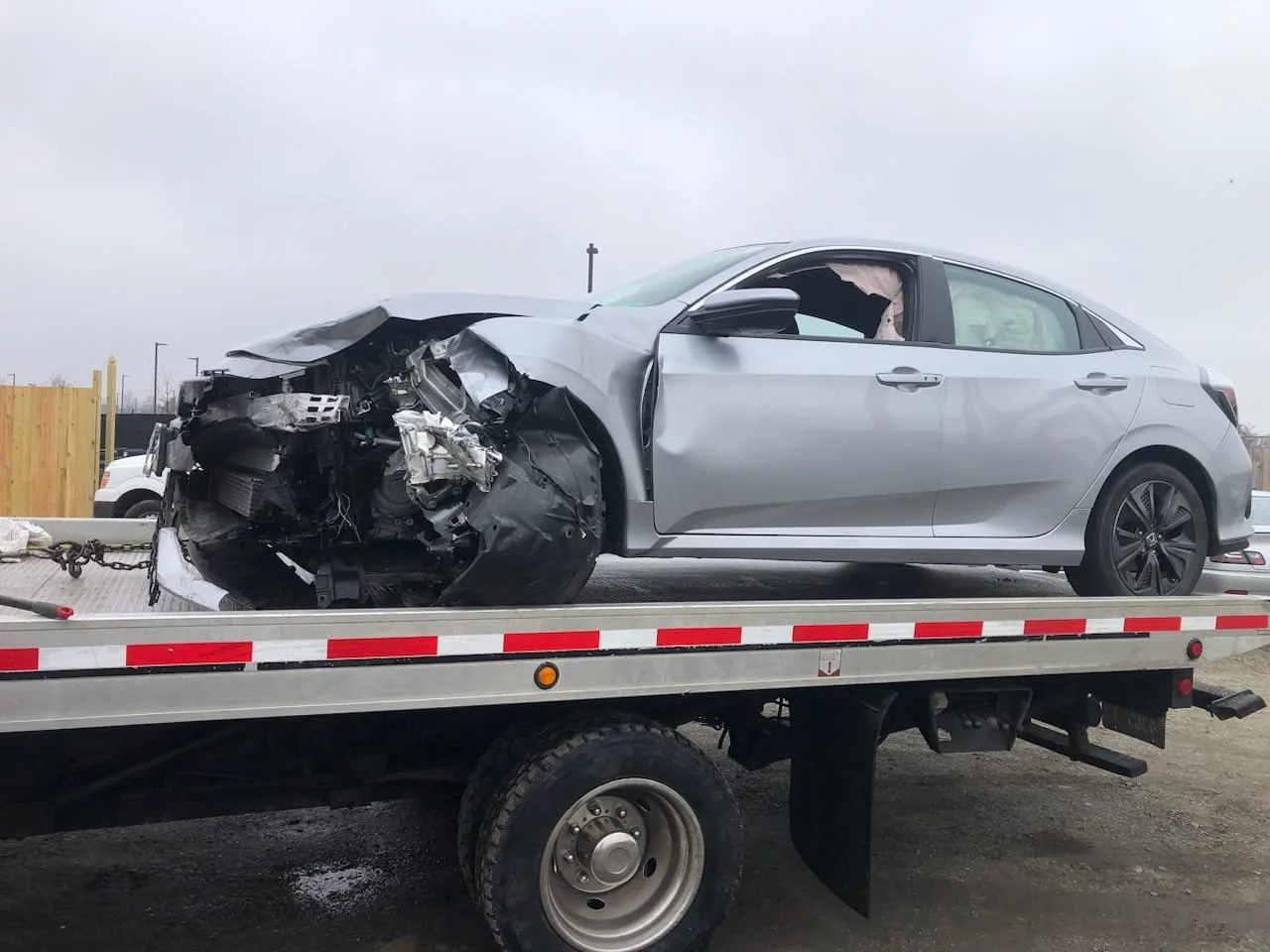 Totaled commuter sedan loaded onto a Dalo Auto Recycling flatbed truck in Northern Virginia