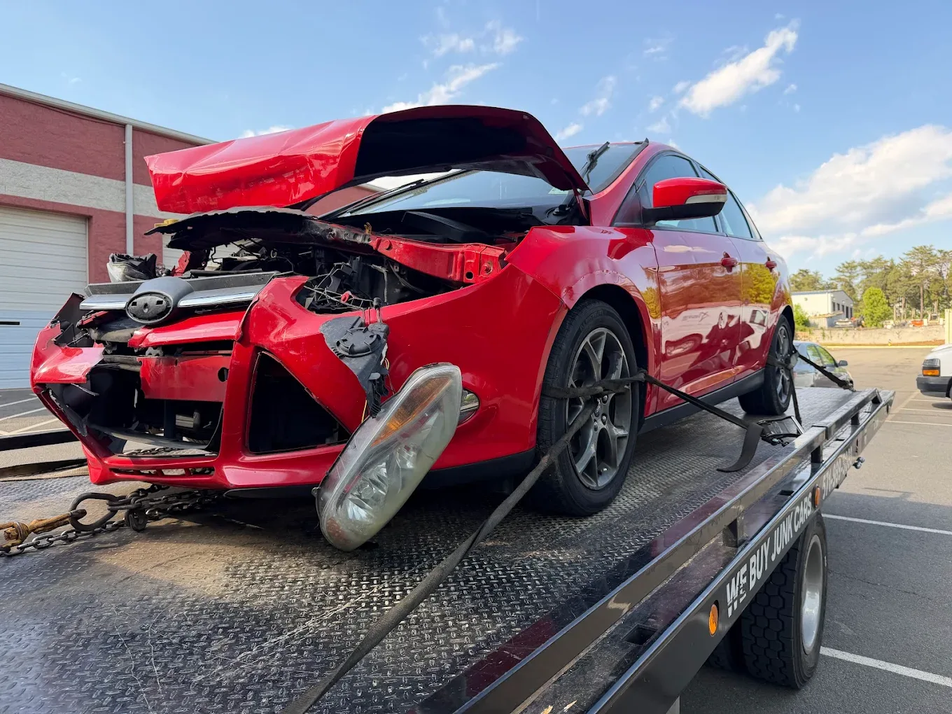 Wrecked commuter vehicle loaded onto a Dalo Auto Recycling flatbed truck in Northern Virginia